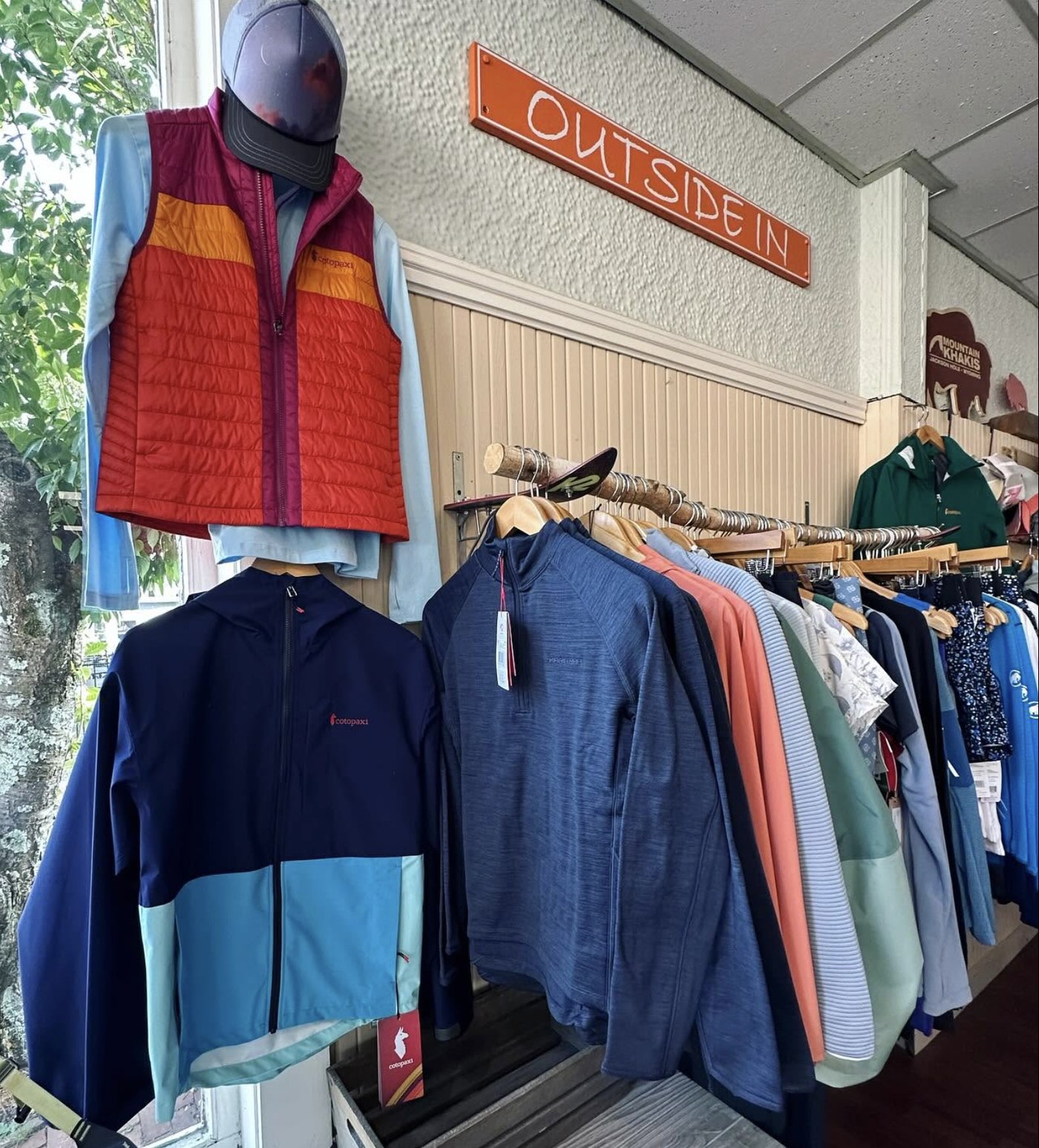 A Cotopaxi puffer vest and jackets displayed beneath the Outside In sign