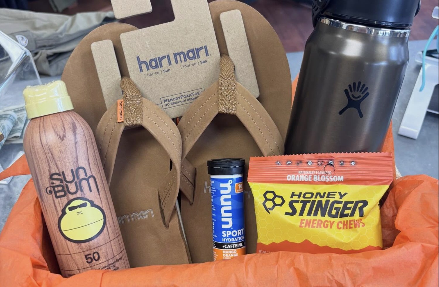Hari Mari sandals, Sun Bum sunscreen, Nuun hydration tabs, Honey Stinger energy chews and a Hydro Flask bottle in a gift box