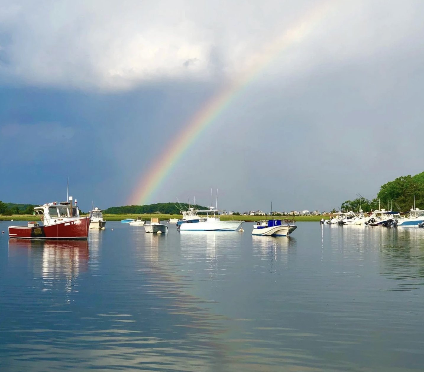 A rainbow arcing over moored boats in Cohasset Harbor after a summer storm