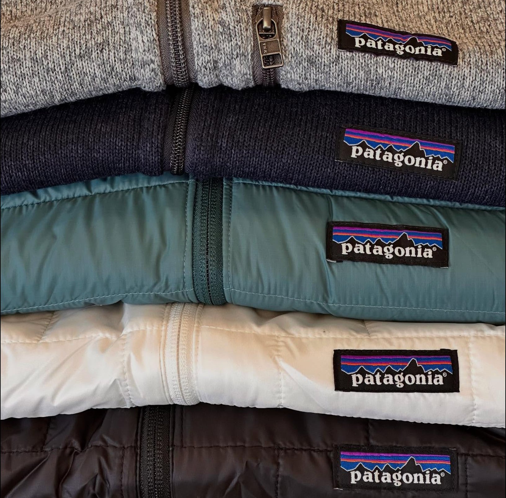 A neatly folded stack of Patagonia fleece and insulated jackets