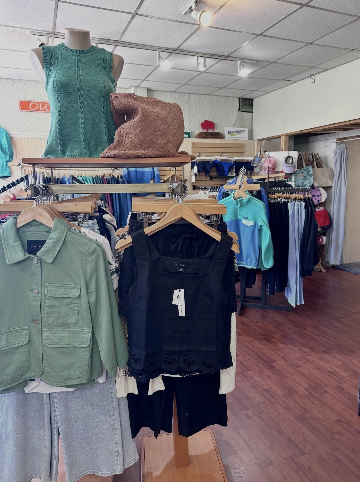 Women's knit tops and a woven bag styled on a display table